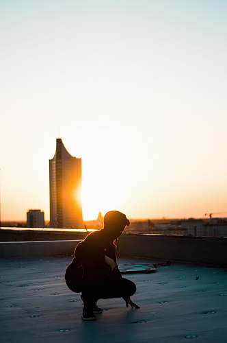 stretch silhouette photography of woman squatting on rooftop sports
